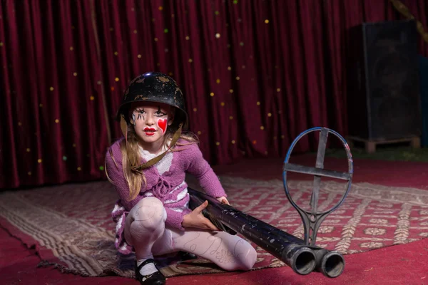 Chica usando casco agacharse en el escenario con pistola — Foto de Stock