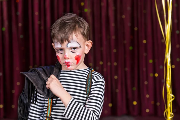 Sulky little boy wearing face paint on stage — Stock Photo, Image