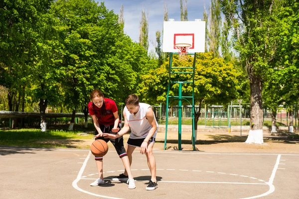 Пара, играющая в баскетбол на открытой площадке — стоковое фото