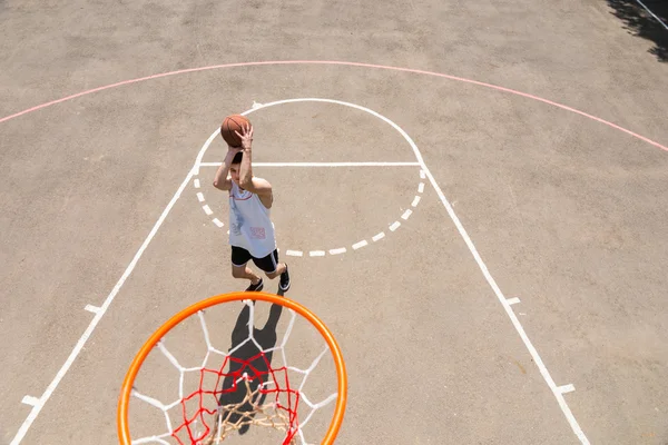 Młody człowiek biorąc strzał na necie na boisko do koszykówki — Zdjęcie stockowe