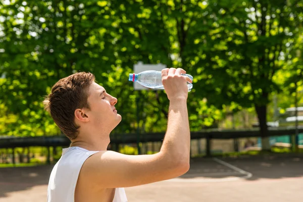 Sportlicher Mann schüttet Wasser aus Flasche ins Gesicht — Stockfoto