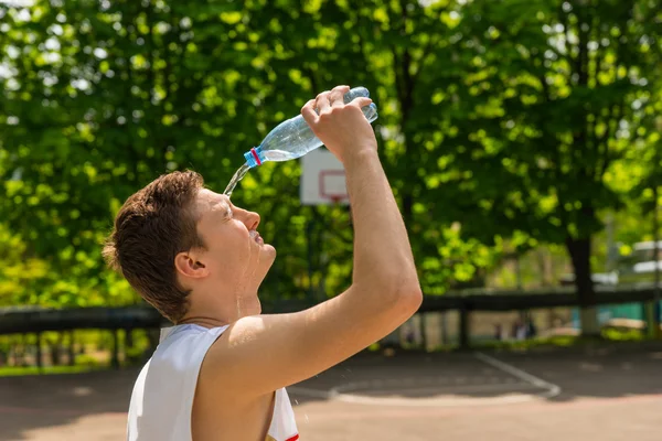 Hombre atlético vertiendo agua de botella en cara — Foto de Stock