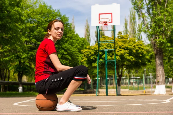 Αθλητική γυναίκα που κάθεται στο μπάσκετ στο γήπεδο — Φωτογραφία Αρχείου