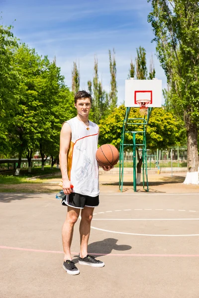 Mann steht auf Basketballplatz und hält Ball — Stockfoto