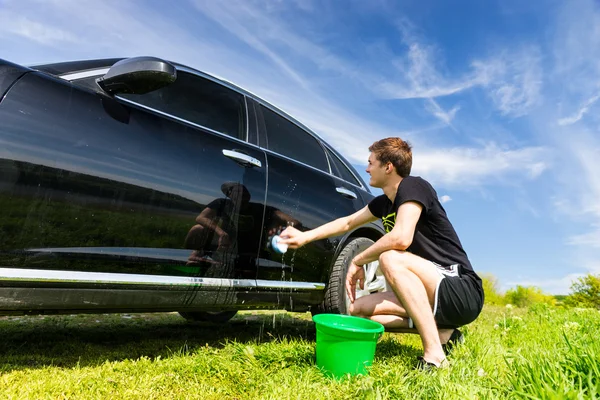 Man wassen auto in veld op zonnige dag — Stockfoto