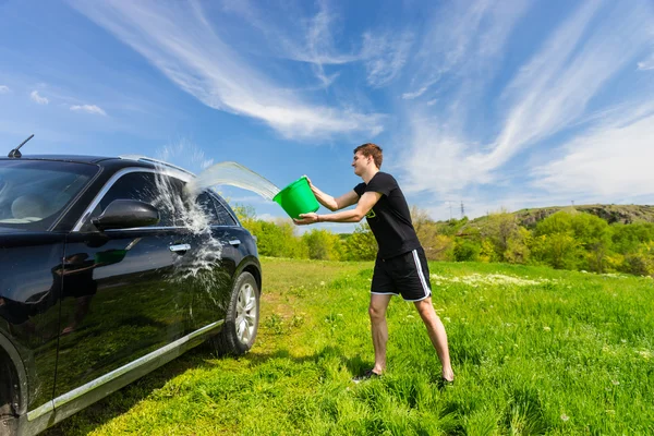 Man tvätta svart bil i grönt fält — Stockfoto