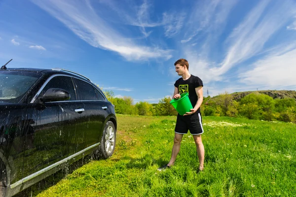 Man tvätta svart bil i grönt fält — Stockfoto