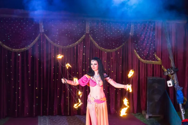 Bailarina de fuego girando bastones llameantes en el escenario — Foto de Stock
