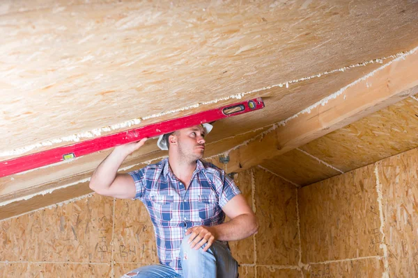 Bauunternehmer nutzt Niveau an der Decke in unfertiger Wohnung — Stockfoto