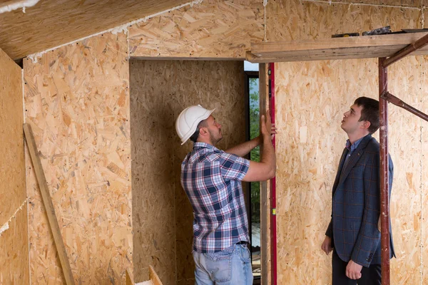 Arquitecto y trabajador comprobando los niveles en el marco de la puerta — Foto de Stock