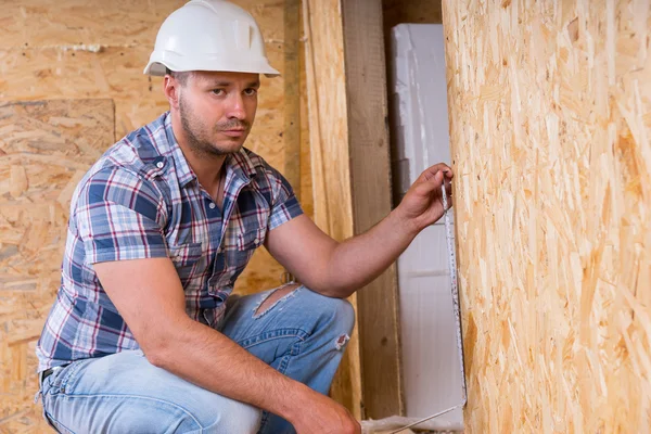 Bauarbeiter misst Türrahmen in unfertiger Wohnung — Stockfoto