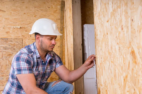 Bauarbeiter misst Türrahmen in unfertiger Wohnung — Stockfoto