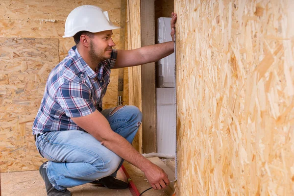 Bauarbeiter misst Türrahmen in unfertiger Wohnung — Stockfoto