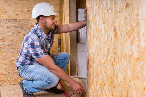 Builder Measuring Door Frame In Unfinished Home