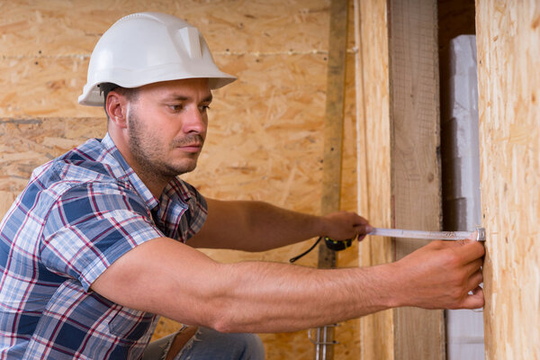 Construction Worker Measuring Width of Door Frame