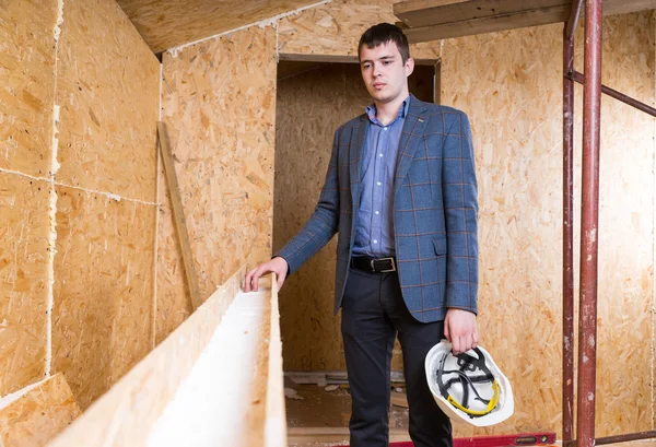 Architecte tenant le chapeau dur à l'intérieur de la maison inachevée — Photo