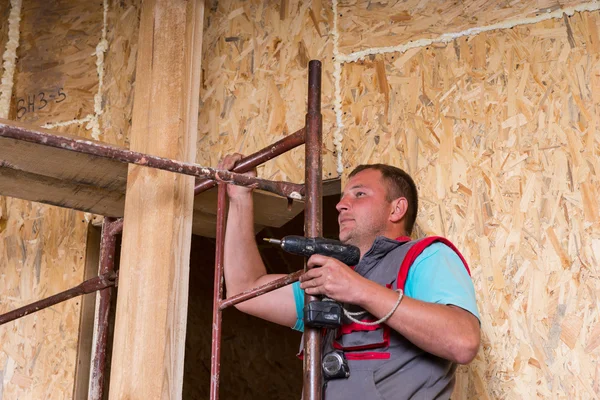 Builder med borr klättra stege av byggnadsställningar — Stockfoto