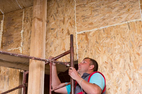 Builder klättring byggnadsställningar i oavslutade hem — Stockfoto