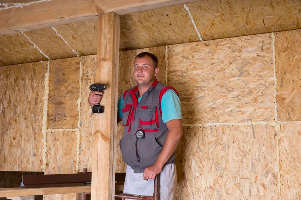 Constructor sosteniendo taladro inalámbrico en casa inacabada — Foto de Stock