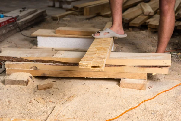 Man die met voet op onafgewerkte hout stapel — Stockfoto