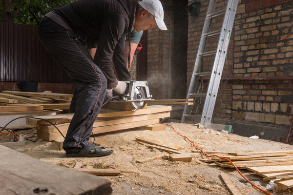Men Using Power Saw to Cut Planks of Wood