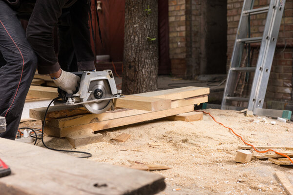 Man Using Power Saw to Cut Planks of Wood