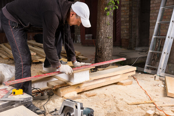Man Using Power Saw to Cut Planks of Wood