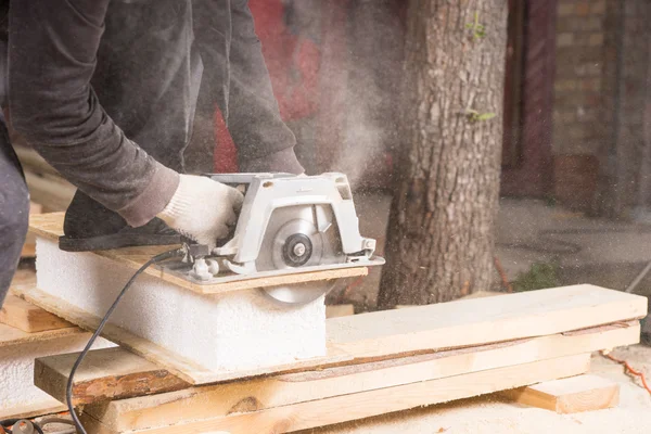Человек, использующий электропилу для резки деревянных досок — стоковое фото