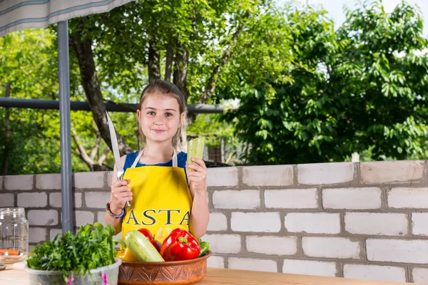 Fille avec grand couteau à table avec des légumes — Photo