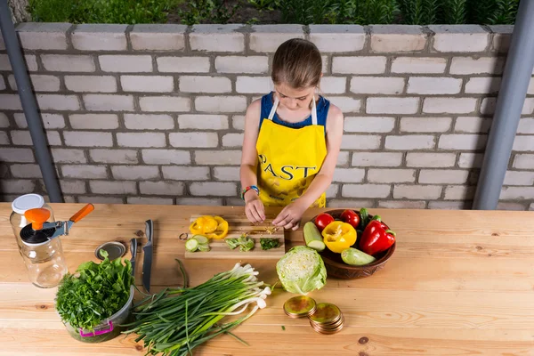 Jong meisje hakken en dobbelen groenten — Stockfoto