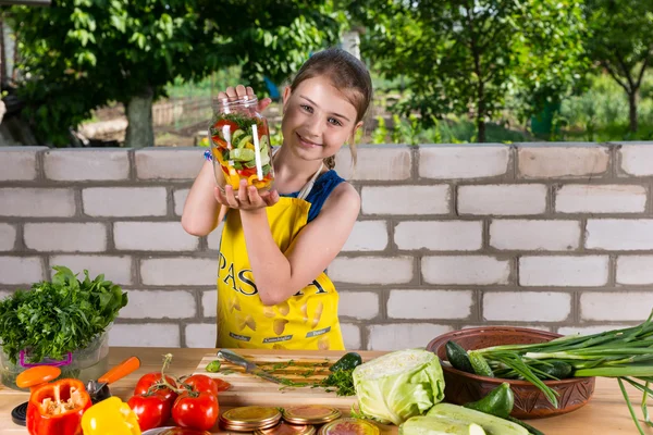 Гордая молодая девушка хвастается овощами в бутылках — стоковое фото