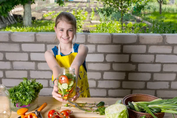 Flicka håller burk fylld med färska skurna grönsaker — Stockfoto