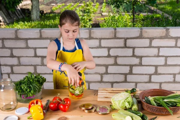 Ernstige jong meisje bottelen verse groenten — Stockfoto