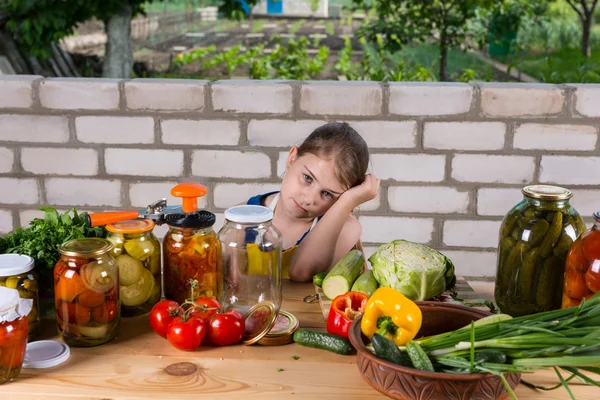 Menina na mesa coberta por vegetais e conservas — Fotografia de Stock