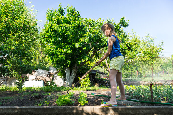 Young girl standing weeding with a hoe