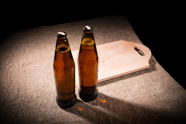 Bottles of Beer and Wooden Cutting Board on Table — Stock Photo, Image