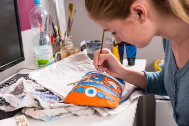 Young woman painting a colorful mask clipart