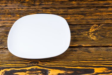 Empty plain white plate on a wood background