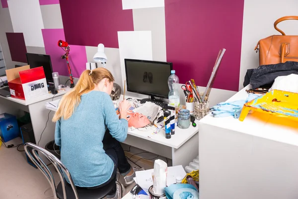 Artist working at her desk painting a mask — Stock Photo, Image