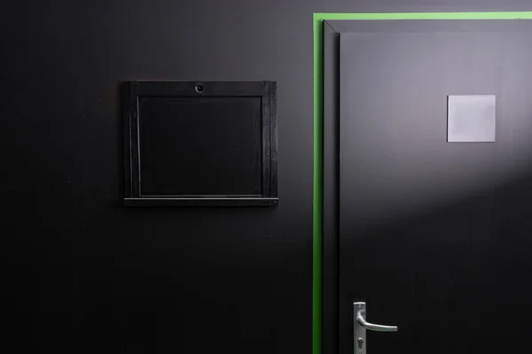 Black wall, door and covered window hatch — Stock Fotó