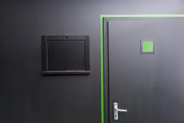 Black door and window hatch on black wall — Φωτογραφία Αρχείου
