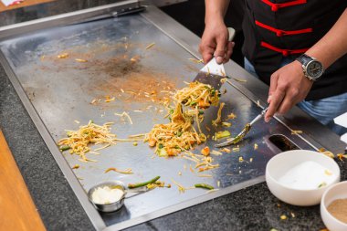 Chef Preparing Asian Noodles on Flat Top Grill