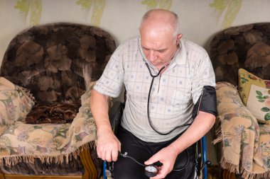Senior Bald Man Checking his Blood Pressure Alone
