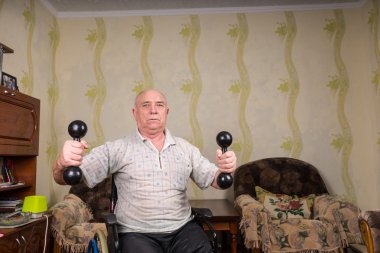 Invalid old man doing exercises with dumbbells
