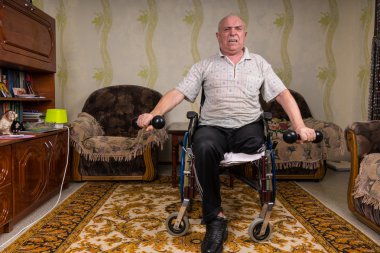 Disabled senior man lifting dumbbells at home