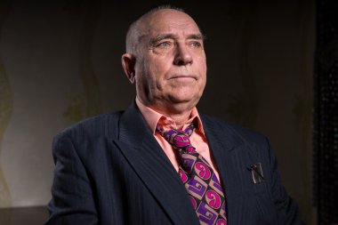 Handsome old businessman is sitting in his room