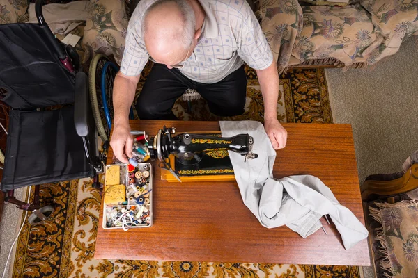 Senior Man Mending Calças com máquina de costura — Fotografia de Stock