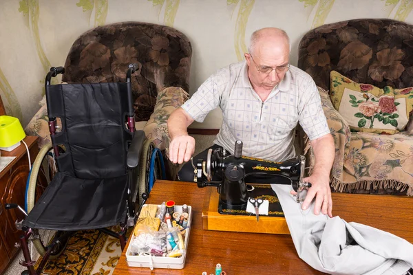 Старший человек использует старомодную швейную машину — стоковое фото