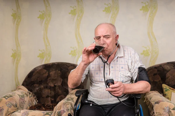 Hombre mayor con esfigmomanómetro bebiendo un jugo — Foto de Stock