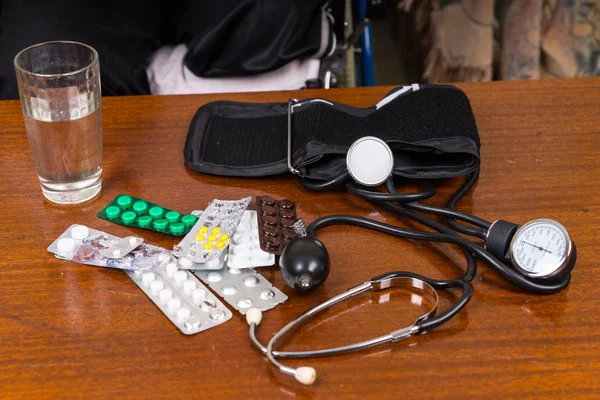 Brazalete de presión arterial en la mesa con medicamentos —  Fotos de Stock